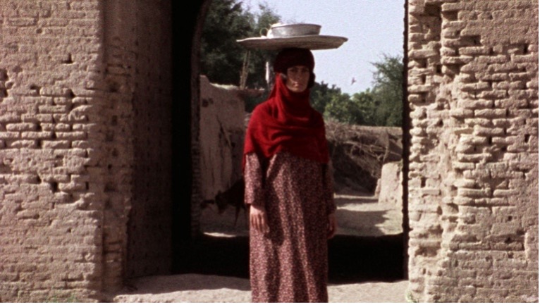 Figure 8 (right): Rūy’bakhayr passing through the village gate with a tray on her head. Still from The Sealed Soil (Khāk-i sar bih muhr), directed by Marvā Nabīlī, 1977.