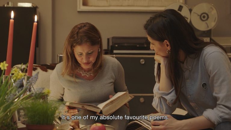 Figure 13: Zaree and her mother seated on a couch, as her mother recites a verse from Hafez. Still from Born in Evin, directed by Maryam Zaree, 2019.