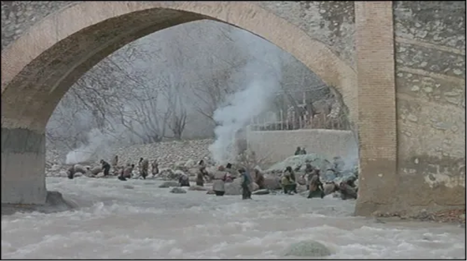 Figure 1: Afghan refugees, including Rahmat, collect stones from the river to sell for income. Baran (2001), directed by Majid Majidi. Accessed via https://www.youtube.com/watch?v=1KWei3v3z1o (00:58:29).